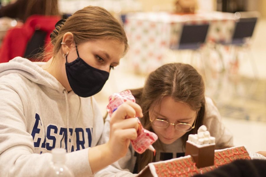 Leonie Badichler, a junior elementary education major, and Evita Schafer, a graduate student, work on decorating their team gingerbread house for the Gingerbread Head-to-Head contest in the University Ballroom in the Martin Luther King Jr. University Union. 