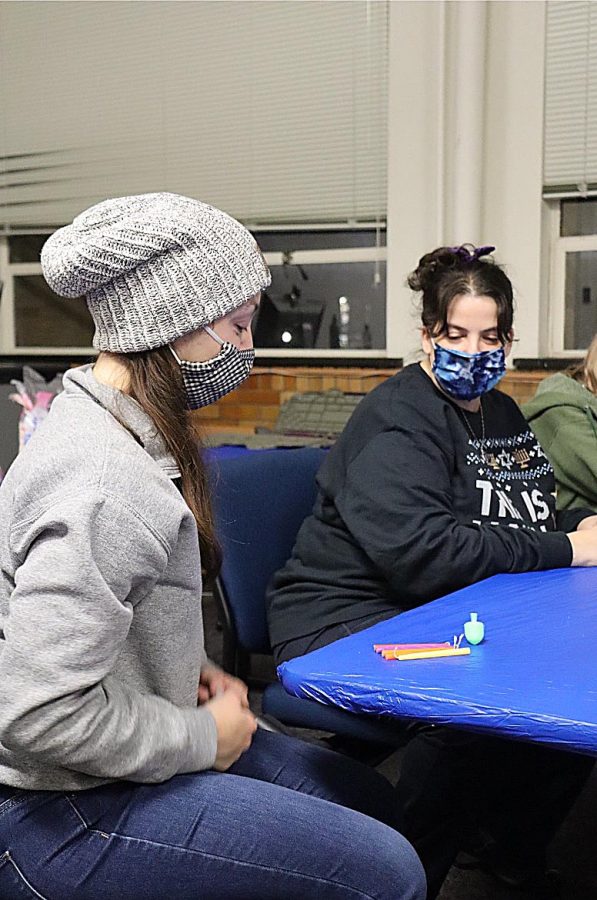 Anna Fishbein, (left) a graduate student studying College Student Affairs, plays a Jewish game called Dreidel after Heather Paul, (right) a senior Jewish Educator and student rabbi at Illini Hillel at the University of Illinois Champaign Urbana, discusses how to play the game to others.