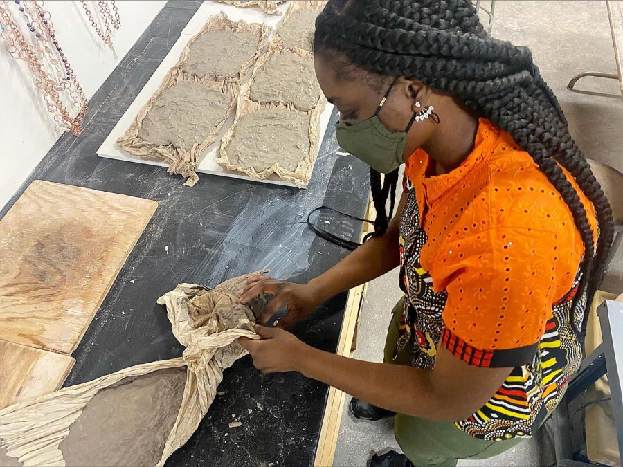 Joy Okokon, a graduate student studying art, peels clay off of a drying towel in the Ceramics Studio in Doudna Fine Arts Center on Saturday.