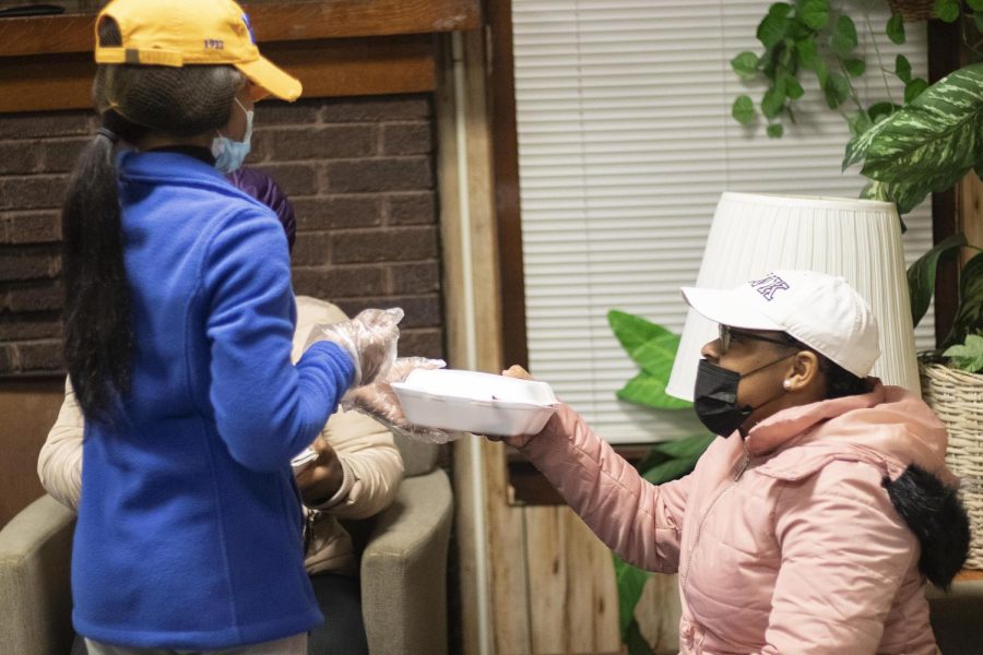 AJ Barnes, a senior psychology major, gets handed her food by Tashajay Silmon, a senior elementary education major, and the vice president of Sigma Gamma Rho Sorority, Incorporated for the Food For the Soul event on Tuesday night at the Cultural Center. Barnes ordered macaroni and cheese, chicken, sweet potatoes, and banana pudding.