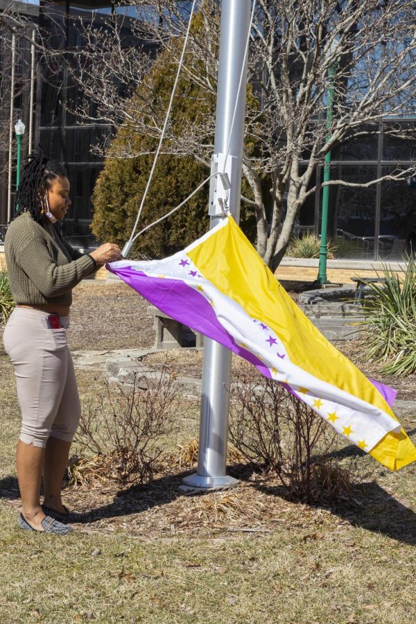 For the beginning of Women’s History Month, Nyjah Lane, a graduate assistant for the Office of Inclusion and Academic Engagement, hangs up the Women’s History month flag in the South Quad on Tuesday afternoon.