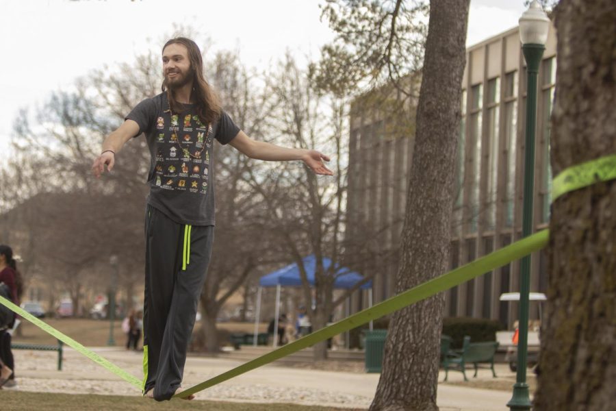 Paul Nau, a junior music major, enjoys the warm weather by slacklining between two trees which he says he learned from watching Youtube videos on Wednesday afternoon in the Library Quad.