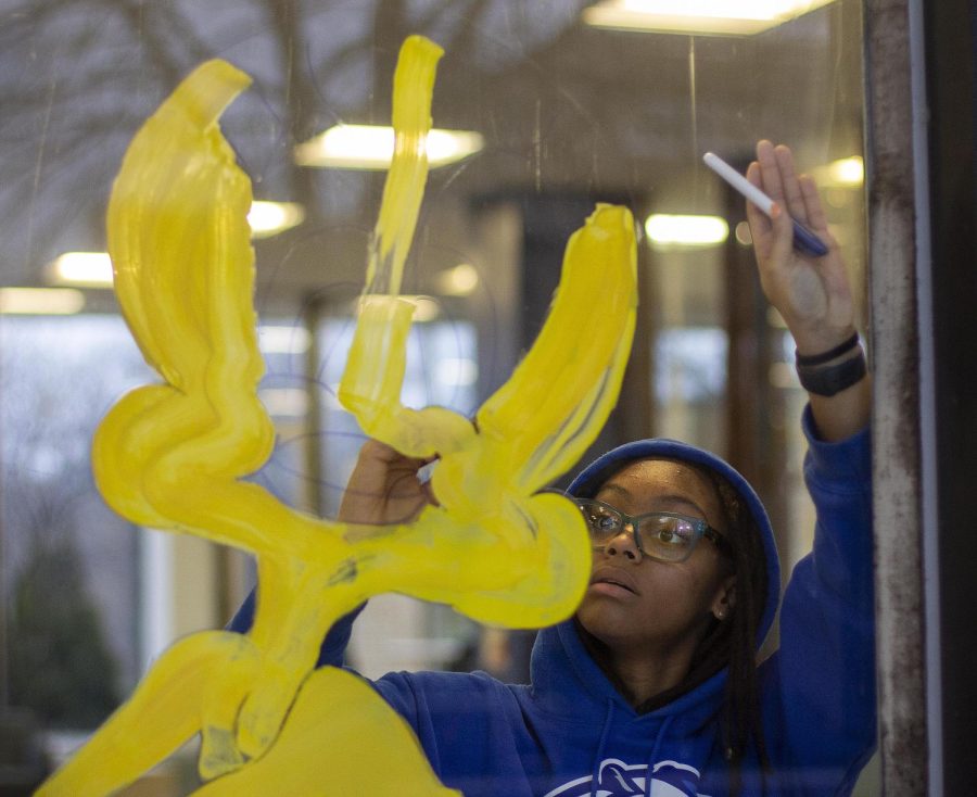 Malaria Fefee, a freshman nursing major, paints Tweetie Bird on Lawson Hall’s windows Wednesday evening.