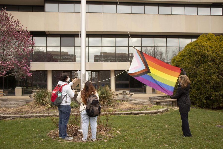 Anne Flaherty, the Vice President for Student Affairs, twists the pride flag in place and helps Payton Ade, a sophomore interpersonal communications major, and Jaclyn Thomas, a senior interpersonal communications major, to raise it on the flag pole in the South Quad Friday afternoon, April 1, 2022 in Charleston, Ill. 