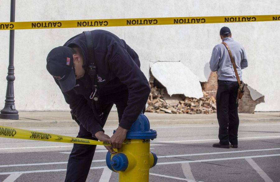 A member of the Charleston Fire Department ties off the perimeter with caution tape while Assistant Fire Chief Tim Meister investigates the building collapse at Smallhorn Law LLC across the street from the Courthouse on the Square. 