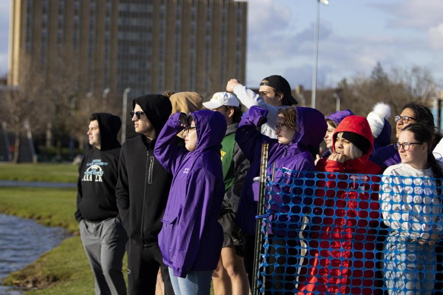 A crowd gathers to watch the other team on the opposite side of the lake struggle to win at the Tugs event for greek week on Monday evening at the Campus Pond on April 18, 2022 at Eastern Ilinois University in Charleston, Ill.