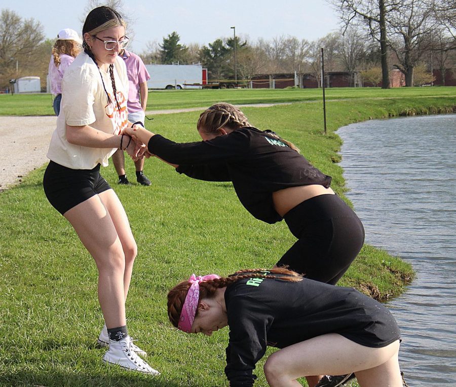 Lauren Cox, a junior management major, helps members of Delta Zeta out of the pond after they lost their round of tugs Friday afternoon at the Campus Pond.