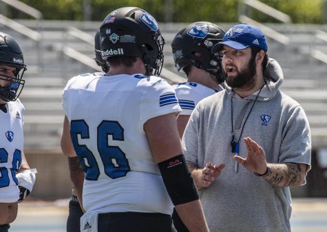 Cole Hoover (right), a graduate assistant for the Eastern football team, talks to Jack Valente (66), a sophomore offensive lineman, before the start of the Alumni Social Spring Game on April 23 at OBrien Field.