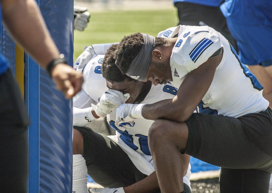 From left, Widerecievers DeAirious Smith (88), a sophomore engineering technology major, and Josh St. Preux, a freshman sport management major, pray before the start of the Alumni Social Spring Game Saturday afternoon at OBrien Field.