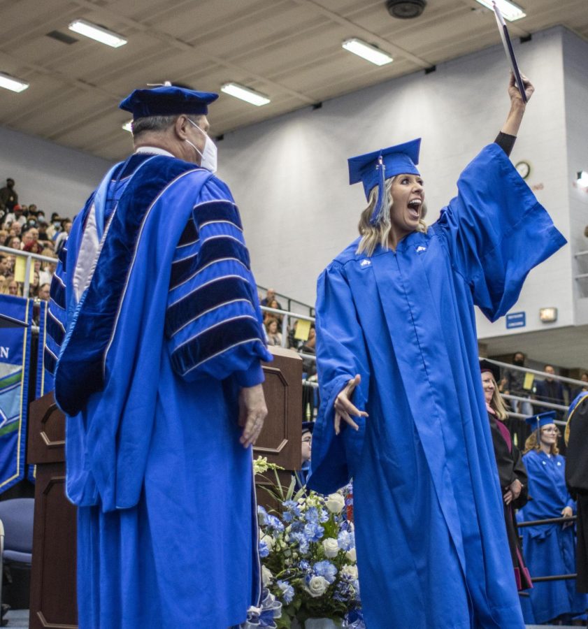A graduate of the Eastern Class of 2022 waves their diploma cover after graduating, showing friends and family during the spring commencement ceremony Saturday afternoon in Lantz Arena.