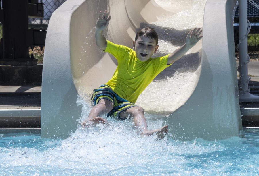 Levi Kubicek, waves his arms in the air while going down the water slide at the Rotary Community Aquatic Center pool Tuesday.