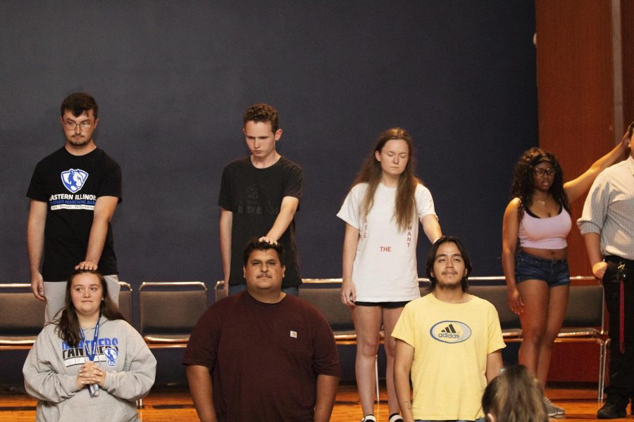A few of the hypnotized students touch volunteer’s heads trying to tell the rest of the audience what they’re thinking about, from instruction by Chris Jones, a hypnotist and comedian.