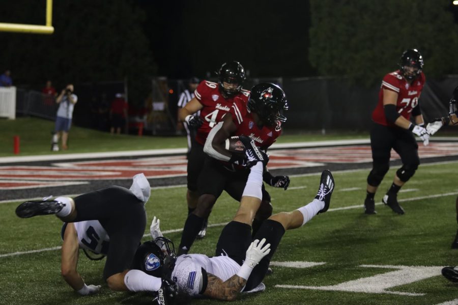 Huskies running back Harrison Waylee, number 30, shakes off two Eastern linebackers during the Panthers season opener against Northern Illinois Thursday night at Huskie Stadium. The Panthers lost 34-27.