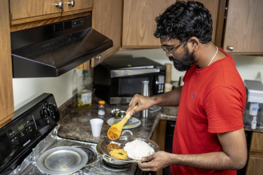 Vighnewsara Manda, a graduate student studying computer information and technology, dishes some tomato masala curry out onto a plate Saturday afternoon at the Parkplace Apartments. Manda said being able to cook Indian food in Charleston, is difficult because the closest Indian market is an hour away in Champaign.