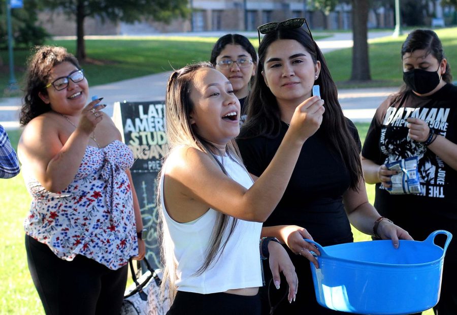 Daniela Munoz, a senior fashion merchandising and design major, pulls a raffle ticket out of a bin during the Latinx social event sponsored by Easterns Latin American Student Organization on Sept. 8 in the Library Quad.