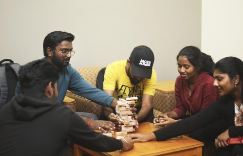 A group of students play Jenga together and try not to knock the blocks down on the fourth floor of Booth Library during Resident Hall Night.