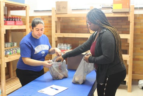 Skylar Oliver, a junior elementary education major, helps Crevaughn Borders, a sophomore philosophy major, bag her food that she picked out from the food pantry inside McAfee Gym Friday afternoon.