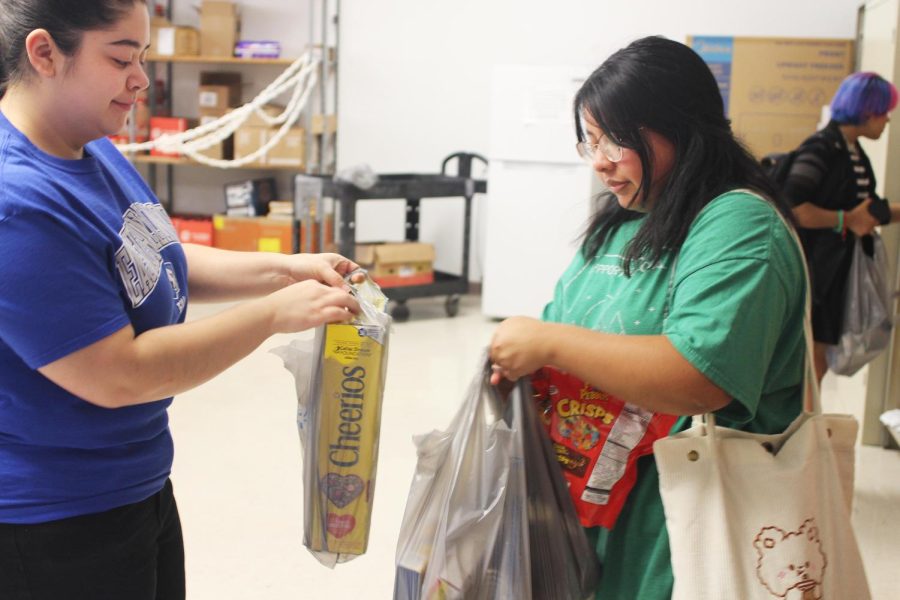 Skylar Oliver, a junior elementary education major, hands Stephanie Riera, a freshman criminology major, bags of various food such as cereal and crisps from the food pantry inside McAfee on Friday afternoon.