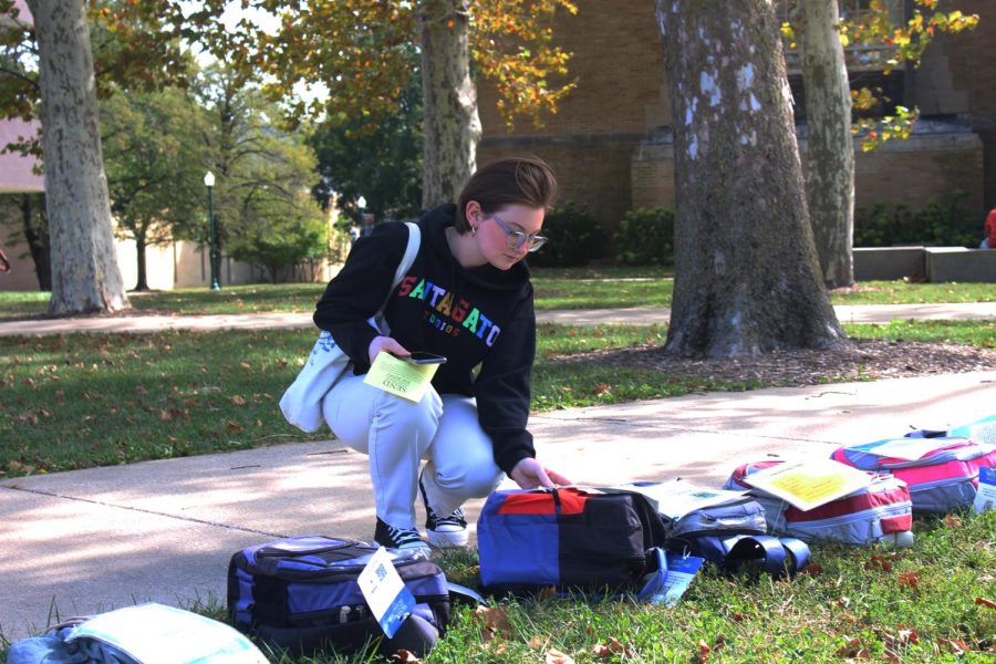 Brooke Wilson, a senior communication studies major, reads stories about people who have lost their lives to suicide and those who have survived at the Send Silence Packing display in the Library Quad Monday afternoon.