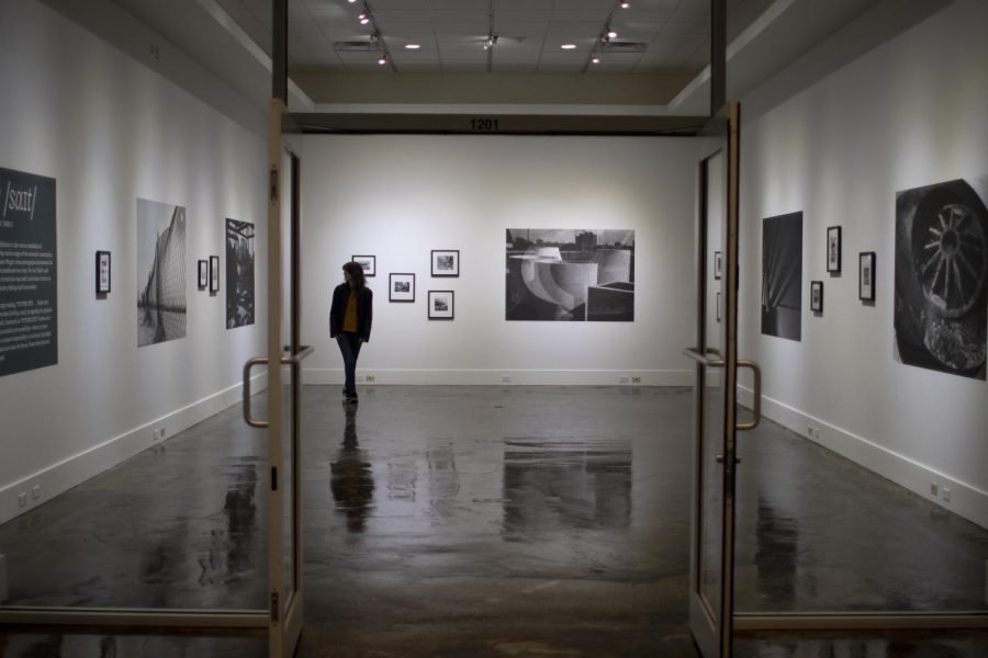 Lily Ames, a masters art student, looks around the photo gallery which features black and white pictures by Gene Wingler from when the Tarble Arts Center was in the process of construction on Friday night.