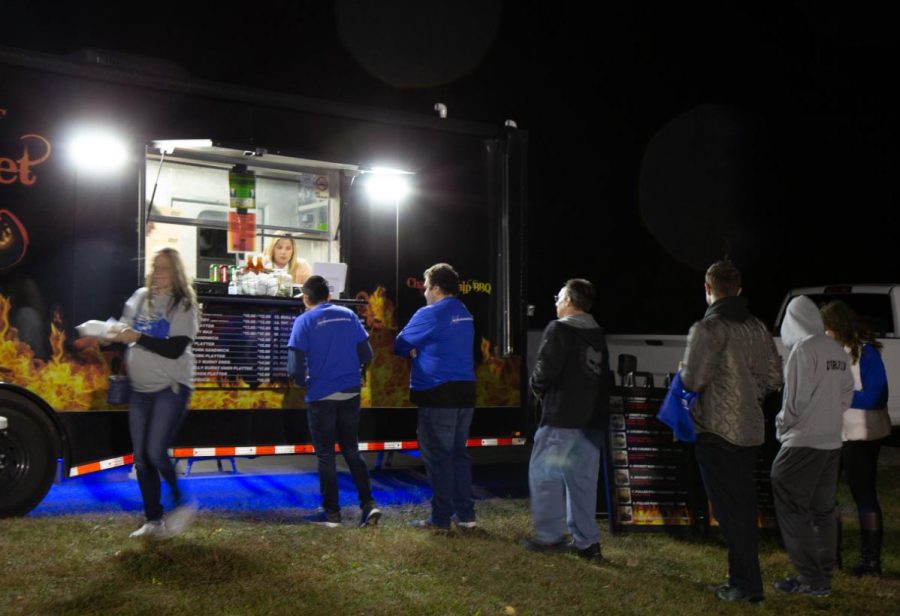 Students and alumni line up a a food truck serving bbq food at O’Brien Field Friday night to celebrate homecoming at a block party. The event included live music, food trucks, a beer garden and game and giveaways.