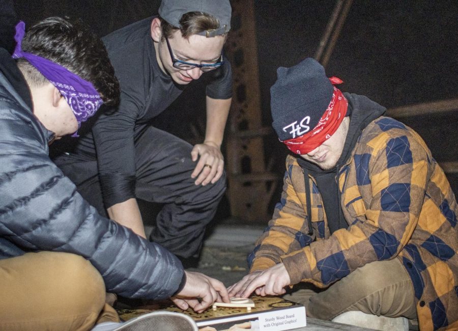Bradyn Wambach (right) and Gentry Cospy (left) hold the planchette while communicating with spirits through an ouija board at Airtight Bridge on Wednesday night, Oct. 12. The group performed a séance in the middle of Airtight Bridge in an attempt to communicate with spirits, with help from Tristen Marlow.  Some spirits include Diana Marie Riordan-Small, a resident of Bradley, Ill, who dissappeared from her home a short time before her remains were found in Airtight Bridges river bed.