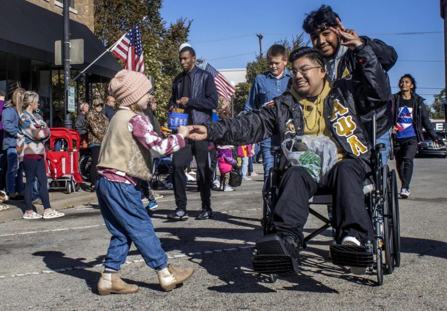 Alpha+Psi+Lambda+President+Luis+Paniagua%2C+a+senior+graphic+major%2C+hands+candy+to+six-year-old+Emma+Turner++during+the+2022+Homecoming+Parade+in+downtown+Charleston+at+the+Square+Saturday+morning.