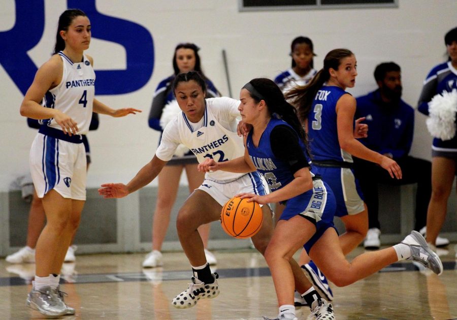 Lariah Washington (22), a senior guard sticks with a Millikin Big Blue player attempting to drive the ball towards the goal in Lantz Arena Thursday evening. Washington led the Panthers with 29 points. The Panthers won 82-78 against the Big Blues. 