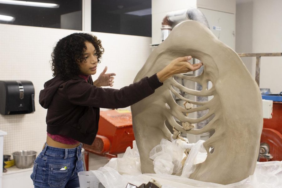 Ashley Spencer, a senior 3D studio major with a focus in ceramics, shows off her newest art piece that shes been working on which she explains is a commentary on being a mixed race artist in Doudna Fine Arts Center Sunday.