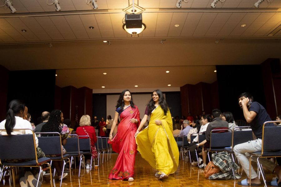 From left, Harika Gardas, a computer technology graduate student, and Harika Malledi, a computer technology graduate student, both from India, walk down the runway together in their traditional sarees from India during the fashion show part of the Global Culture Night in the Grand Ballroom of Martin Luther King Jr. University Union.