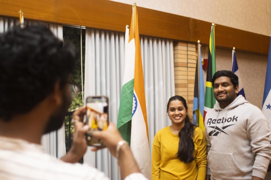 During the Global Culture Night event, Vigneshneswara Manda, a computer technology graduate student, takes a picture of husband, Bhaskar Neerati, and wife, Shwetha Kokkula, a computer technology graduate student, by the Indian flag in the Grand Ballroom of Martin Luther King Jr. University Union.
