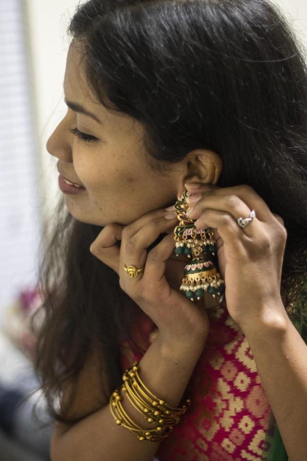 Sajani Reddy Singapuram, a computer technology graduate student, in her room of her apartment, chooses earrings that she mentions are from north India and is the first time she is wearing them because she is from south India.