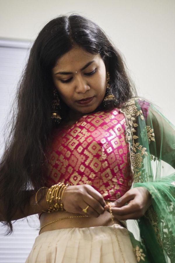 Sajani Reddy Singapuram, a computer technology graduate student, in her room of her apartment, puts on waist jewelry as apart of her outfit.
