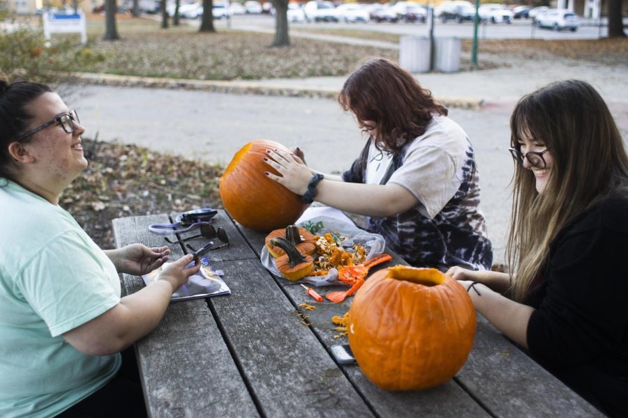 Brooke Renaud, a freshman english major, Emily Hood, a freshman accounting major, and Frannie Harris, a freshman psychology major, carve pumpkins together behind Thomas Hall late afternoon on Wednesday.