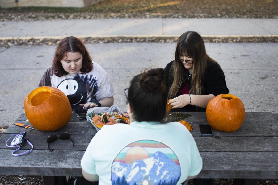 From back left, Brooke Renaud, a freshman english major, Frannie Harris, a freshman psychology major, and Emily Hood, a freshman accounting major, work on drawing designs on pumpkins and taking out the insides in order to start carving them behind Thomas Hall Wednesday late afternoon.