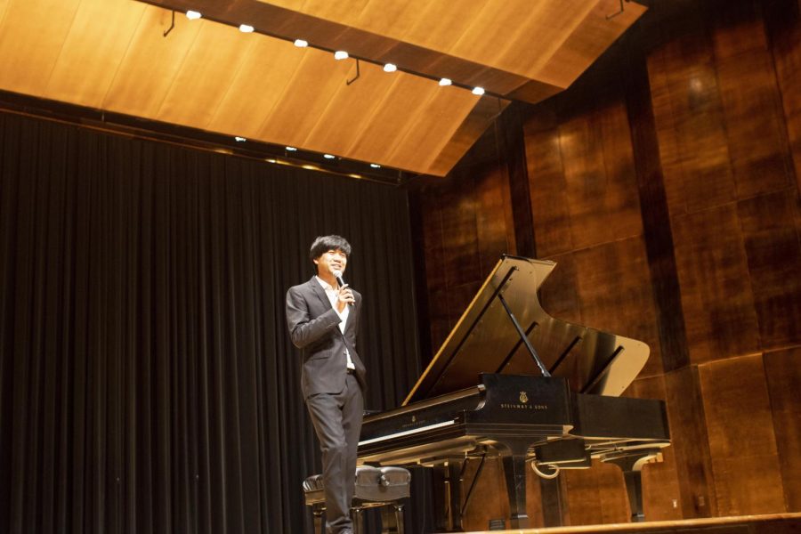 Sean Chen, a pianist, explains the background story of the three pieces he will perform to the audience in the Dvorak Concert Hall of Doudna Fine Arts Center Friday night. Chen received a standing ovation from the audience members at the end of his performance.