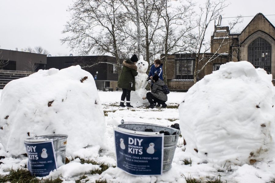 Abigail Riti, a freshman psychology major, Riley Bauer, a junior english major, and Silas Roemer, a freshman physics major, find sticks to use as the arms for the final touches of their snowman named Byobert in the Library Quad Wednesday afternoon.