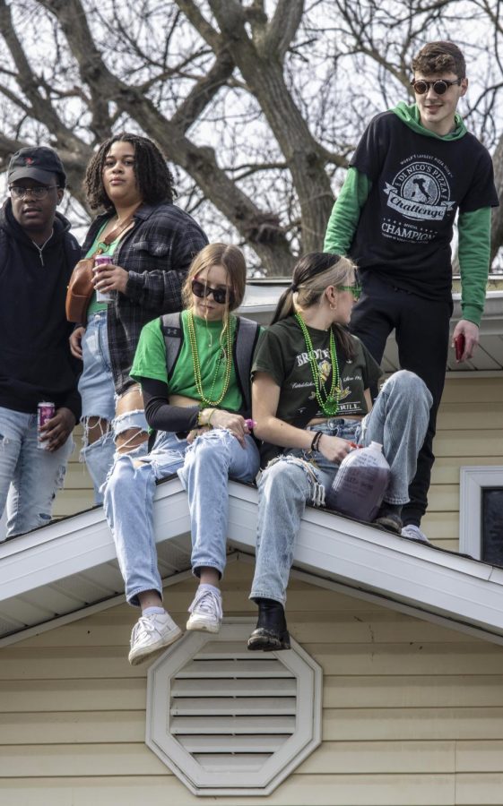 Partygoers sit on the roof of the second Unofficial party house Saturday morning.