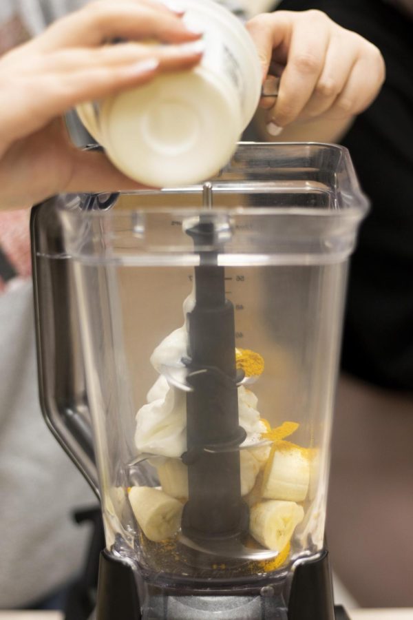 For the Golden Vagina smoothie, Alyssa Marino, a senior English major, blends together milk, pineapple, banana, turmeric, protein powder, and greek yogurt at the At Your Cervix cooking class Monday evening in Klehm Hall.