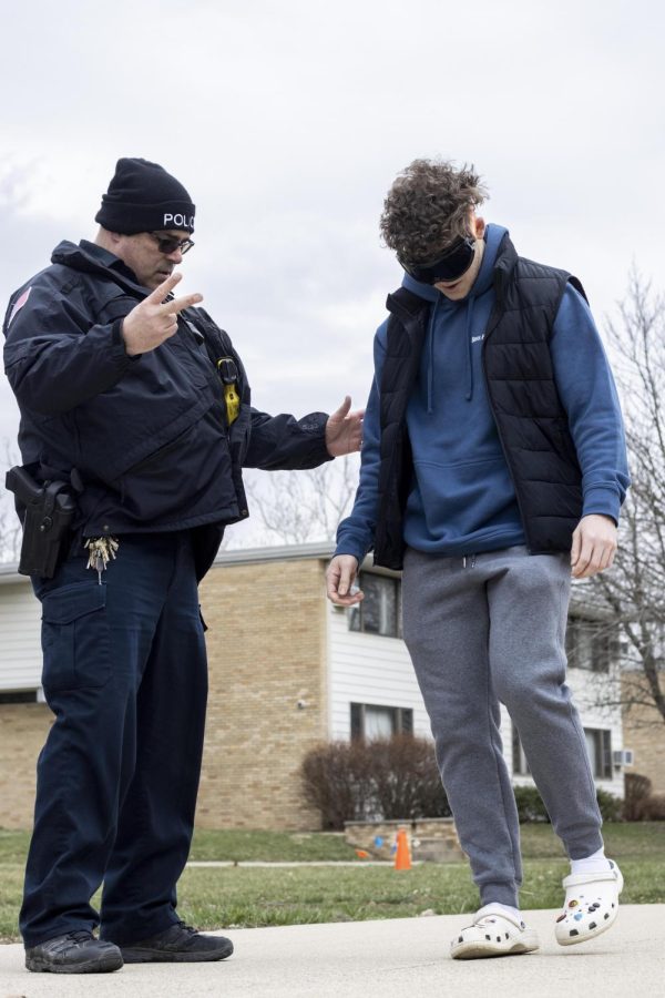 Shane Davis, a junior finance major, tries to walk in a straight line with the drunk goggles on while Officer Cook helps him not fall over at the darty event hosted by student government on the Library Quad Thursday afternoon.
