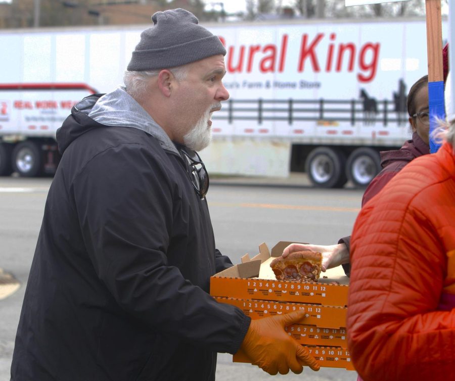 Jeff Duck, an academic advisor, passes out pizza that was sent to members of the EIU-UPI via Doordash. Duck also served pulled pork sandwiches he made with ingredients paid for by the union. Union members had lunch between picketing and a rally at Morton Park Thursday afternoon.