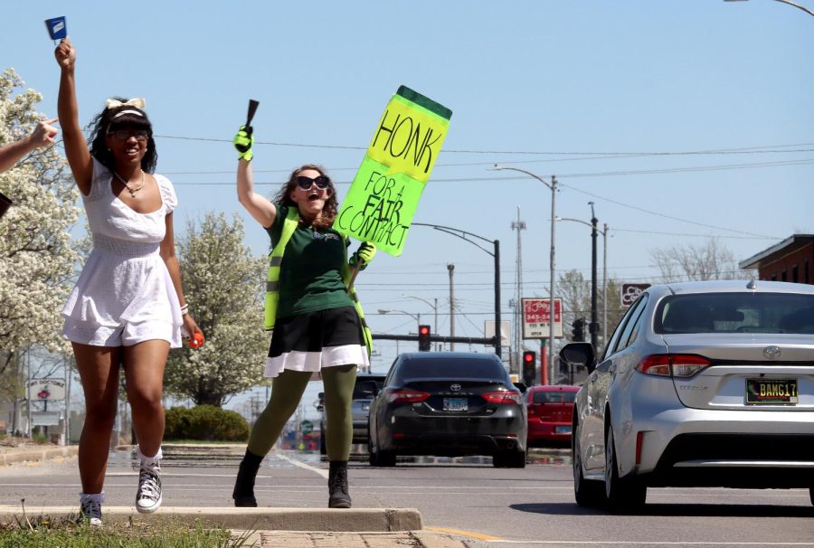 Tatiana Stringer (left), a sophomore health administration major, rings a cowbell and blows an airhorn encouraging drivers to honk in support of the union contract negotiations outside Old Main on their fourth day of picketing for a fair contract Tuesday morning.