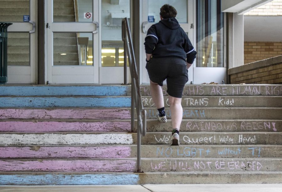 Kaden Howard, a senior language arts teacher education major, walks up the east stairs to the Martin Luther King Jr. University Union have affirming messages and a transgender flag in chalk.