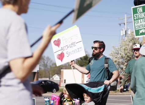 Spencer Spear, an educational leadership graduate student, supports his wife, Shelly Spear, an English instructor, in her fight for a fair contract in front of Old Main Wednesday afternoon.