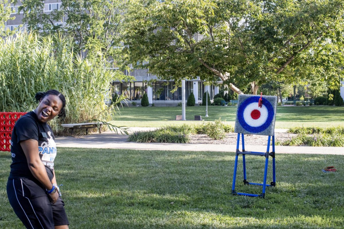 During the Black Student Union field day event in South Quad, Shay Edmond, a senior sociology major, throws one of the axes at the target but misses the board.