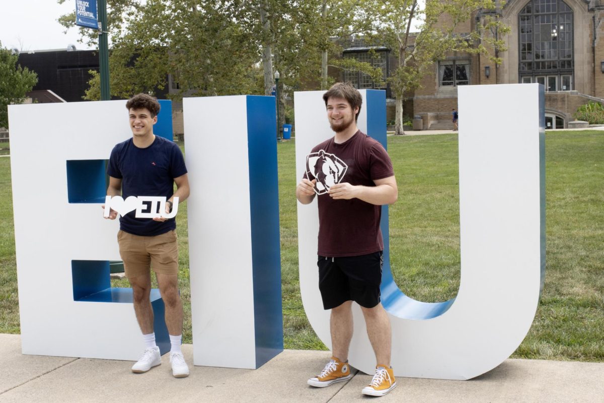 Kaleb Hemrich (left), a senior environmental biology major, and Jason Miller (right), a senior pre-biological sciences major, poses at Easterns First Day of Class Photo set up outside of the Library Quad.