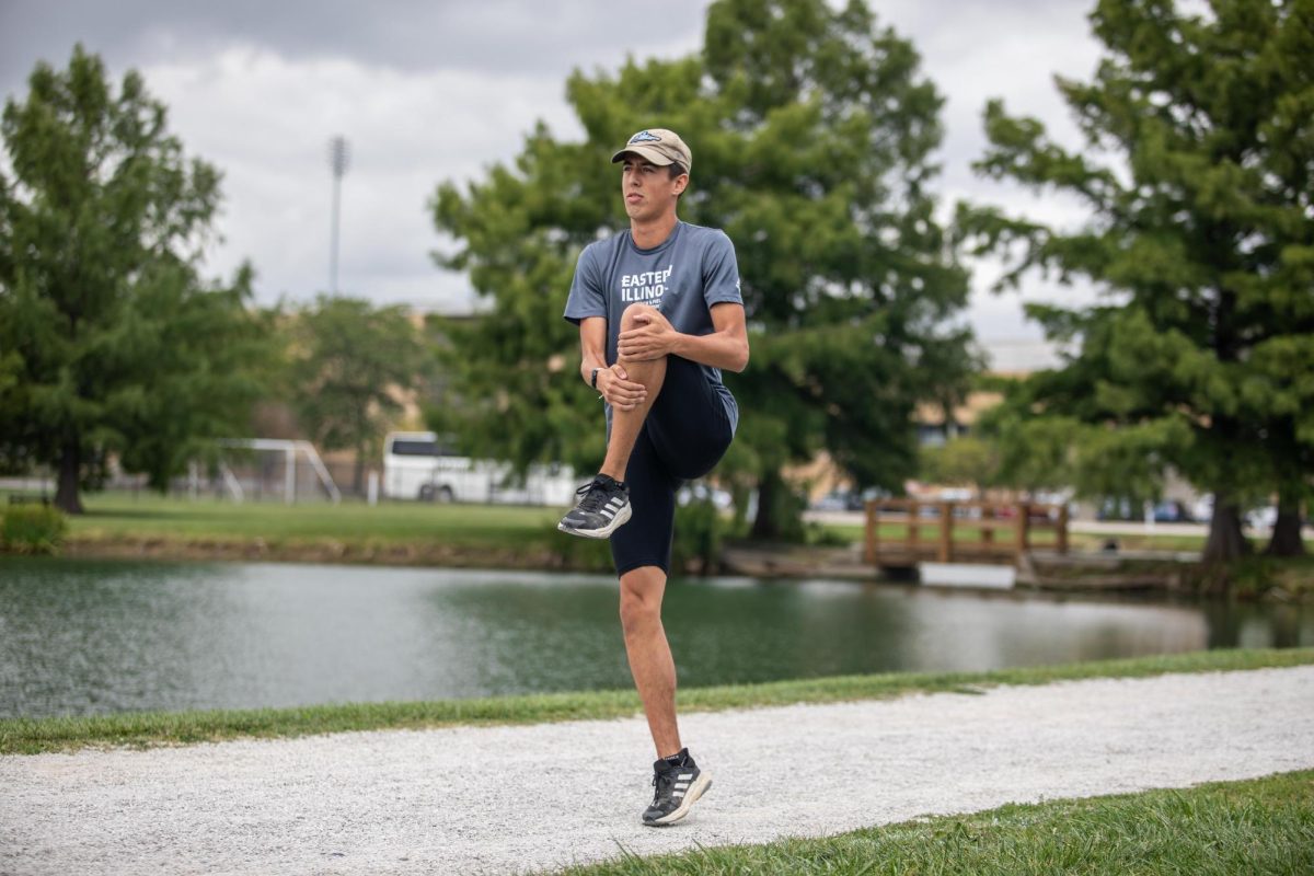 Adam Swanson, a cross country fifth year student stretches and jogs before running a mile at Eastern Illinois Campus Pond Saturday afternoon