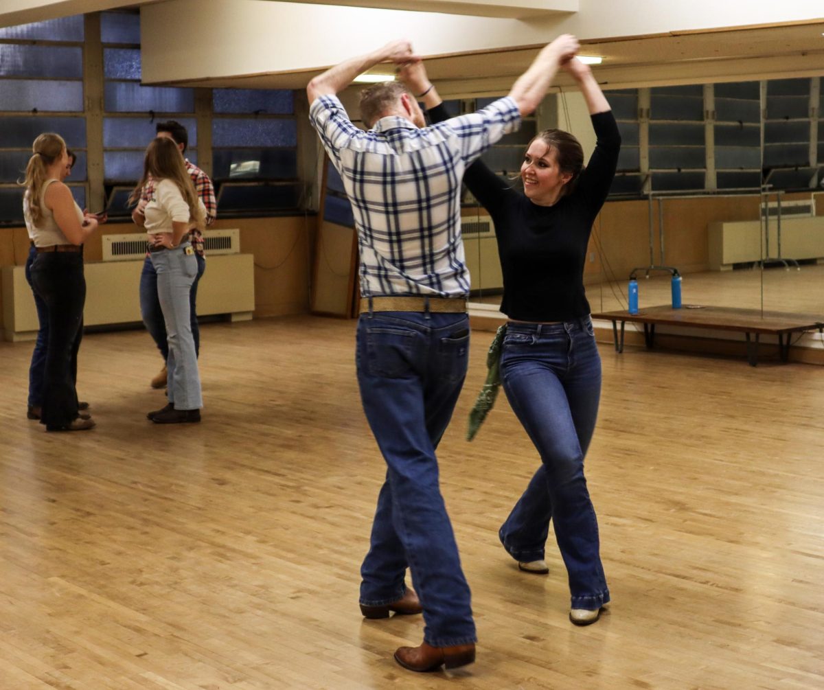 Kayla Tomaszkiewicz, a Junior communication disorders and science major, practices a routine with dance partner before line dancing club practice begins in McAfee Gym underground Friday evening.
