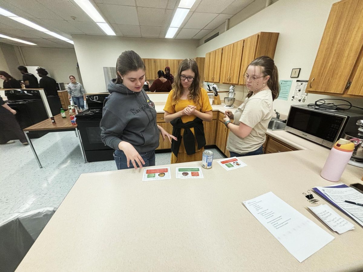 From left, Shayla Taylor, Madalyn Stead, and Hannah Hunt look at the Mediterranean diet recipes during the Healthy Cooking 101 session in Klehm Hall.