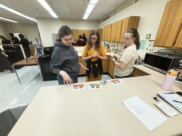 From left, Shayla Taylor, Madalyn Stead, and Hannah Hunt look at the Mediterranean diet recipes during the Healthy Cooking 101 session in Klehm Hall.